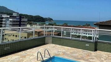 A rooftop swimming pool with a clear view of the ocean and surrounding buildings.