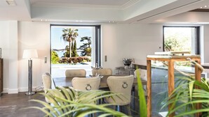 A modern dining area with a view of a landscaped garden and a pool. - Superbe Villa vue mer sur st Tropez (Sainte-Maxime)