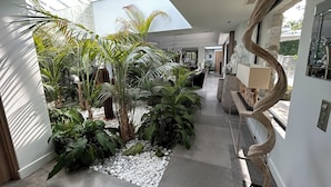 A modern interior with a central garden area, a curved wooden structure, and a glass ceiling. - Superbe Villa vue mer sur st Tropez (Sainte-Maxime)