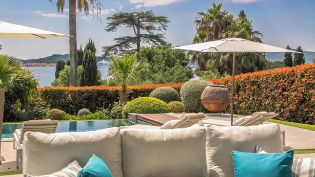 A poolside area with lounge chairs and umbrellas, a view of the sea, and well-maintained landscaping. - Superbe Villa vue mer sur st Tropez (Sainte-Maxime)