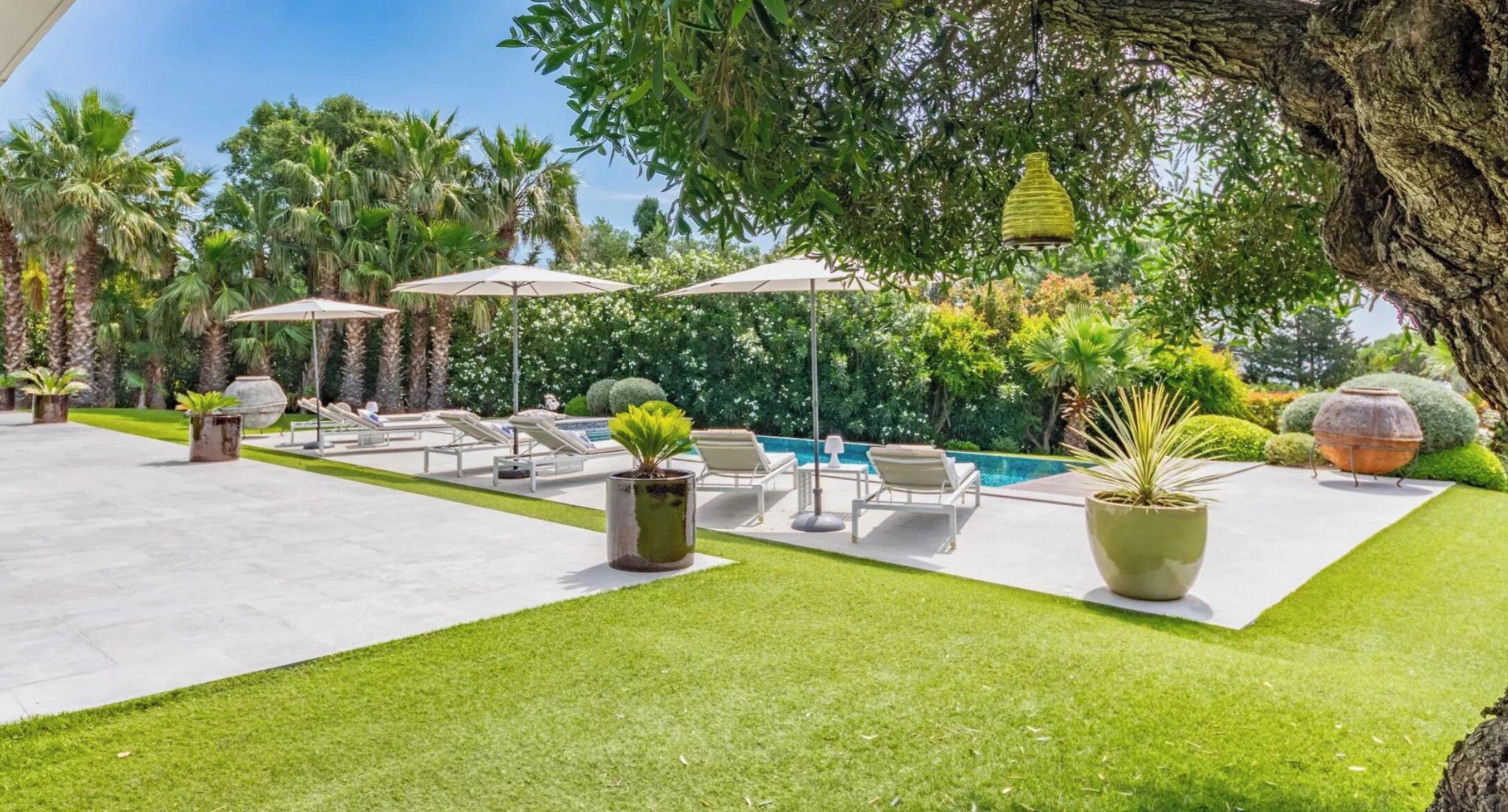 A poolside area with lounge chairs, umbrellas, and a barbecue grill.