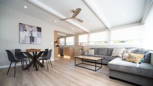 A spacious living area with a dining table, chairs, a sofa, and a ceiling fan. - La Jolla Windansea Luxury Cottage (San Diego)