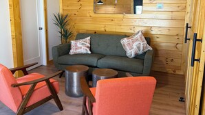 A cozy room with a wooden wall, a sofa, two armchairs, a small table, and a mirror. - Charming 1BR Barn Retreat – Close to Hospitals, Parks & Town in  Mooresville (Mooresville)