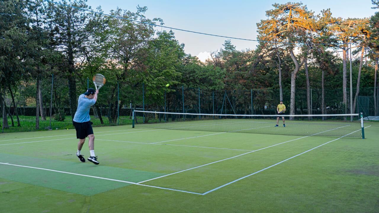 Ein Tennisplatz mit Netz, umgeben von Bäumen.