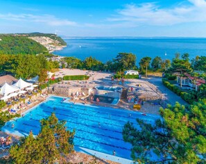 A large outdoor swimming pool with multiple lanes, surrounded by lounge areas and a scenic view of the sea. - Residence Mare Azzurro, Falesie Apartment for 6 people   (Duino Aurisina)