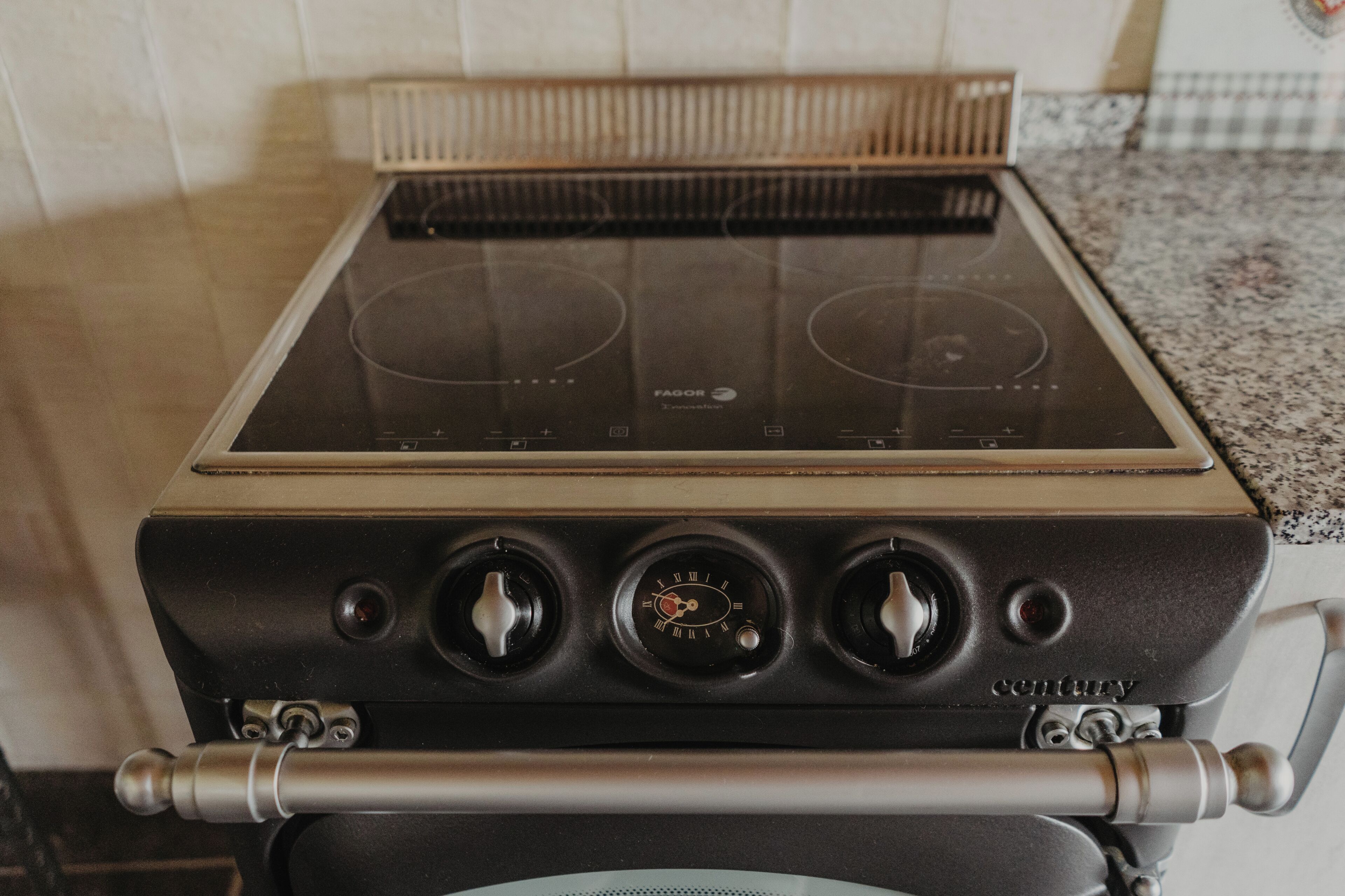 Una cocina con estufa, horno y campana extractora.