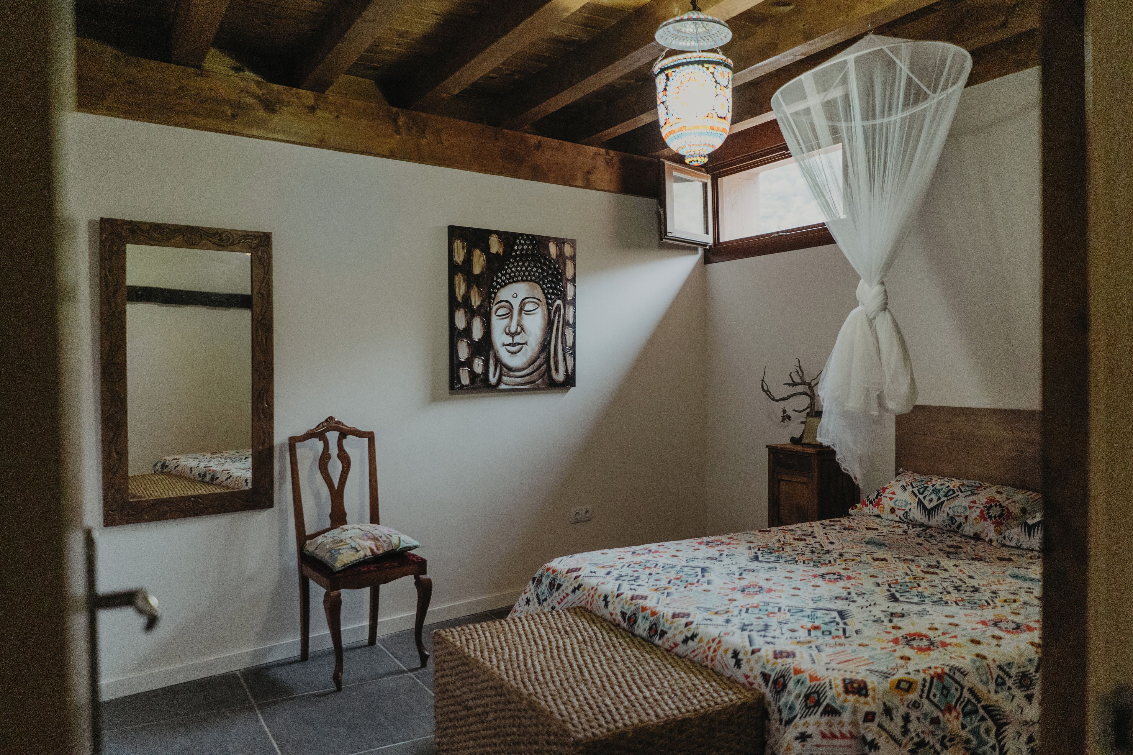 Une chambre à coucher avec un lit, une chaise, un miroir et un tableau accroché au mur.