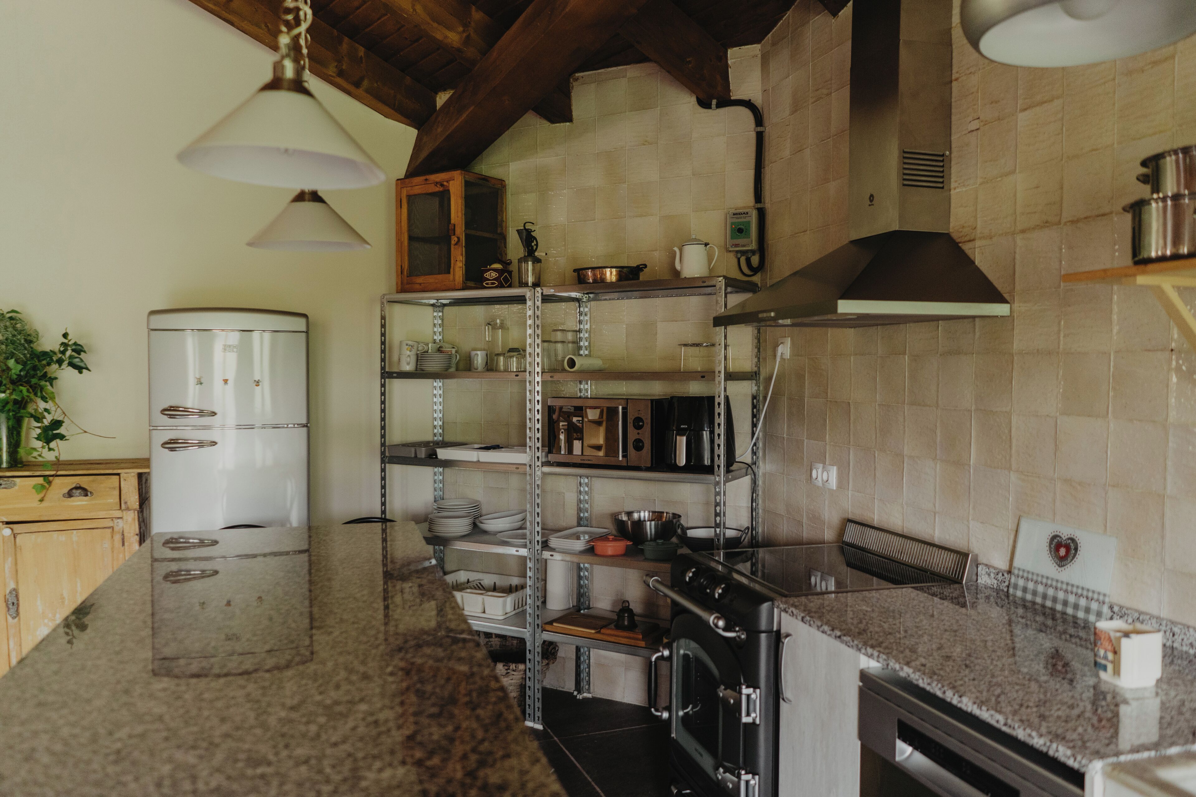 Une cuisine équipée d’appareils électroménagers en acier inoxydable, d’un meuble en bois et d’un luminaire suspendu.