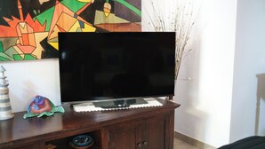 A flat-screen TV on a wooden cabinet with a decorative item and a remote control. - Petali di Rosa – A Due Passi dalla Spiaggia (Loiri)