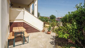 A patio with a wooden table and bench, a small staircase, and potted plants.