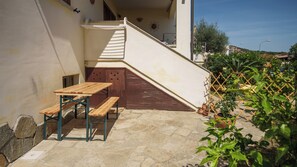 A patio with a wooden table and bench, a small staircase, and potted plants.