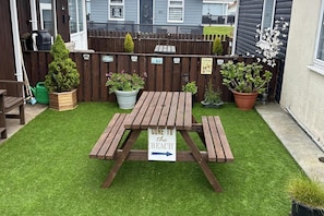 A wooden picnic table with a sign indicating a direction to the beach. - Cozy Seaside Chalet in Bridlington (Bridlington)