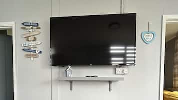 Un televisor de pantalla plana montado en la pared con un estante debajo.