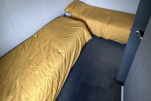 A small, single-bed room with a dark floor and a gold-colored bedspread. - Cozy Seaside Chalet in Bridlington (Bridlington)