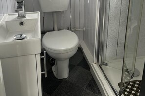 A bathroom with a white toilet, a sink, and a shower area. - Cozy Seaside Chalet in Bridlington (Bridlington)