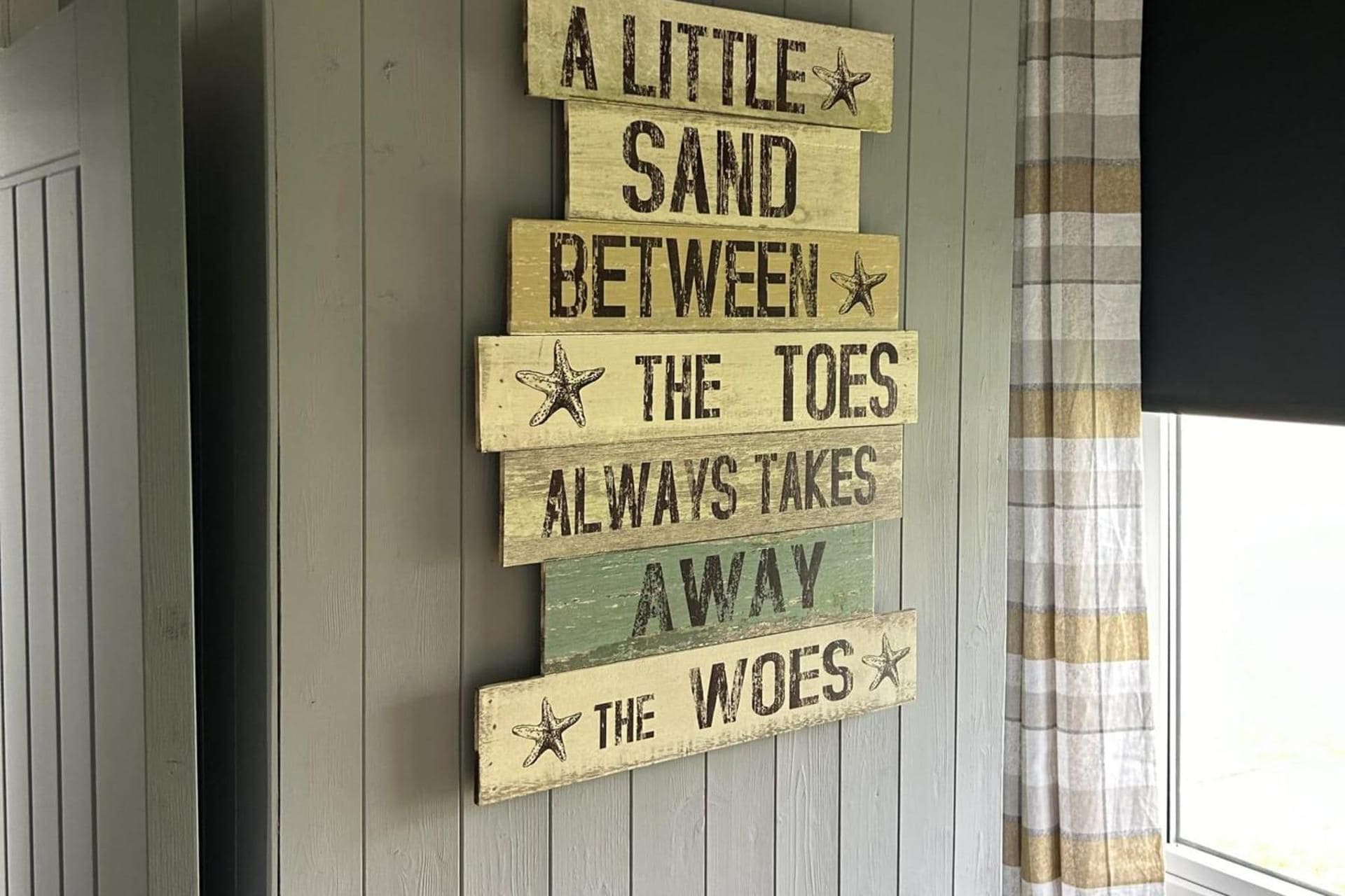 Un letrero de madera con temática náutica, que incluye texto y decoraciones de estrellas de mar.