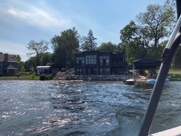 A waterfront property with a large house, a dock, and a boat.