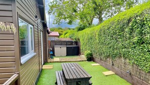 A backyard with a wooden deck, a barbecue area, and a well-maintained hedge. - Large 3 bed Chalet -sleeps 6- dog Friendly- Garden (Bridlington)