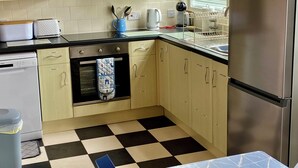 A kitchen with light wooden cabinets, a black and white checkered floor, a stainless steel refrigerator, and a dish rack. - Large 3 bed Chalet -sleeps 6- dog Friendly- Garden (Bridlington)