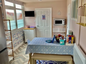 A compact kitchen with a table, microwave, and various kitchen items. - Large 3 bed Chalet -sleeps 6- dog Friendly- Garden (Bridlington)