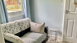 A room with a black leather sofa, a patterned throw blanket, a small stool, and a woven rug. - Large 3 bed Chalet -sleeps 6- dog Friendly- Garden (Bridlington)