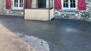 Un edificio de piedra con contraventanas rojas, una ventana pequeña y un porche delantero.