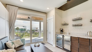 A modern kitchen with a built-in oven, a coffee machine, and wine glasses on a shelf. - Rooftop Deck & Hot Tub: Mexico Beach Home! (Mexico Beach)
