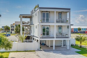 Un edificio residencial de varios pisos con un porche cubierto, un balcón en el piso superior y un camino de acceso con portón.