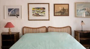 Een kamer met een bed, twee nachtkastjes en drie kunstwerken in lijsten aan de muur.