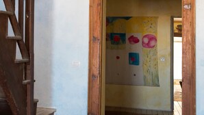 A wooden staircase leading to a room with a colorful abstract painting on the wall. - Sardinia RE - Alma Boh Mien Stunning View (Alghero)