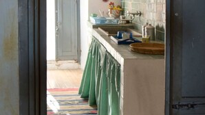 A narrow kitchen with a wooden floor, a green apron hanging, and a hanging light fixture. - Sardinia RE - Alma Boh Mien Stunning View (Alghero)