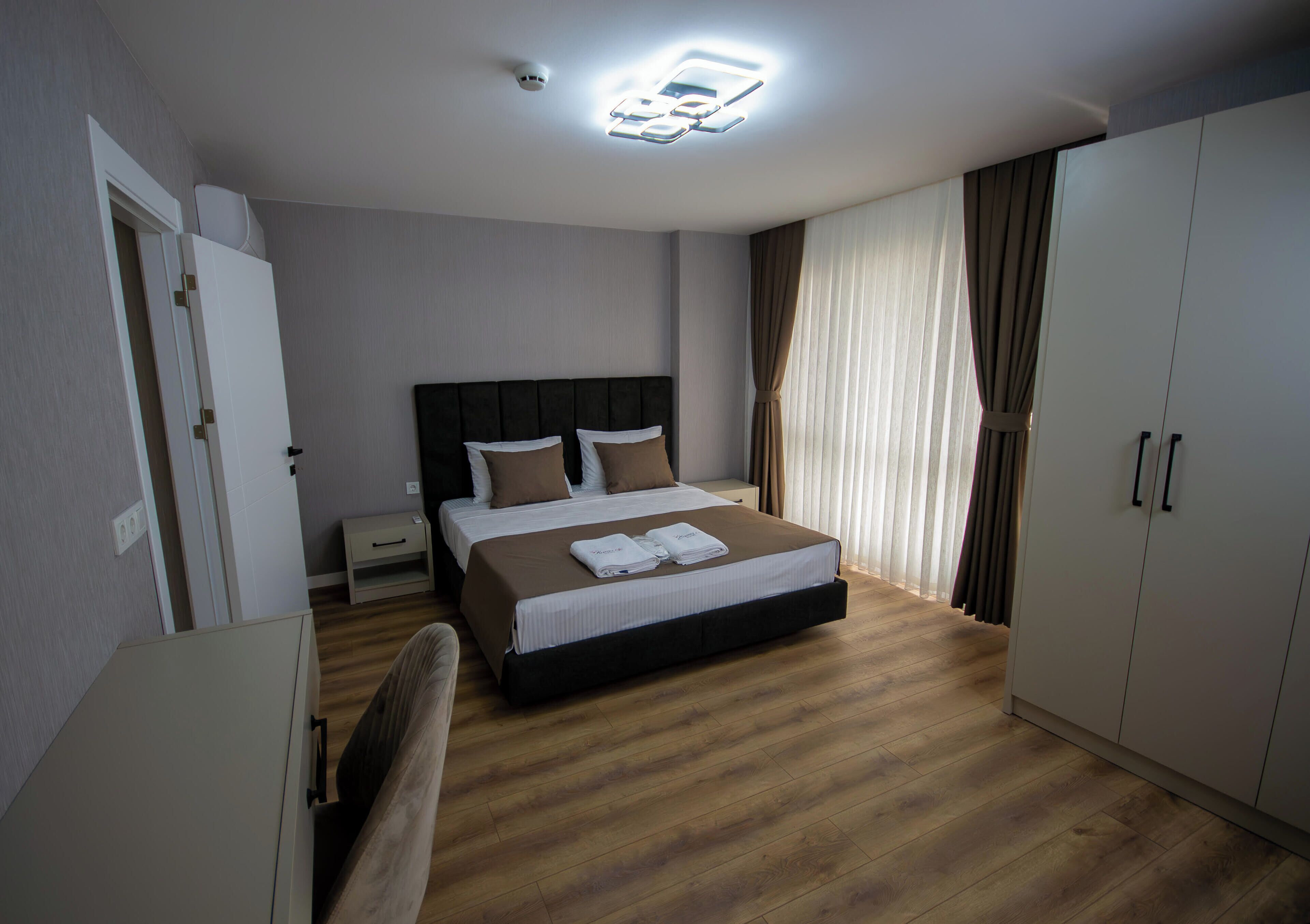 A hotel room with a bed, a desk, a wardrobe, and a ceiling light.