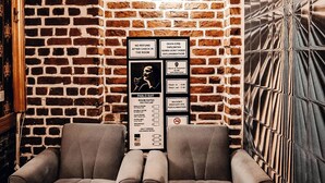 A room with a brick wall, a sofa, a mirror, and a sign with room rates and rules. - Pablo Suit Hotel (Istanbul)