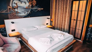 A modern hotel room with a large bed, wooden flooring, a headboard with built-in lighting, a wall mural, and a sliding door. - Pablo Suit Hotel (Istanbul)