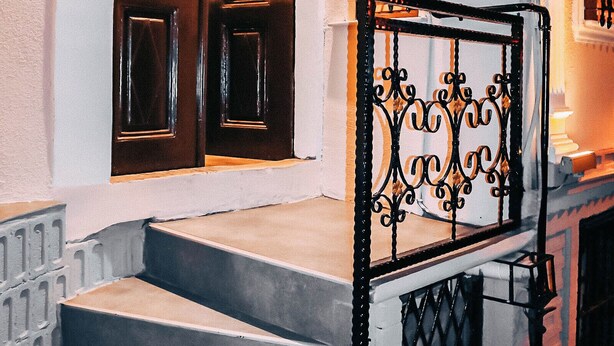 A staircase with a wrought iron railing leading to a door with decorative panels. - Pablo Suit Hotel (Istanbul)