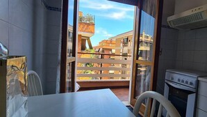 A kitchen with a view of neighboring buildings, a dining area with a table and chairs, and a small oven.