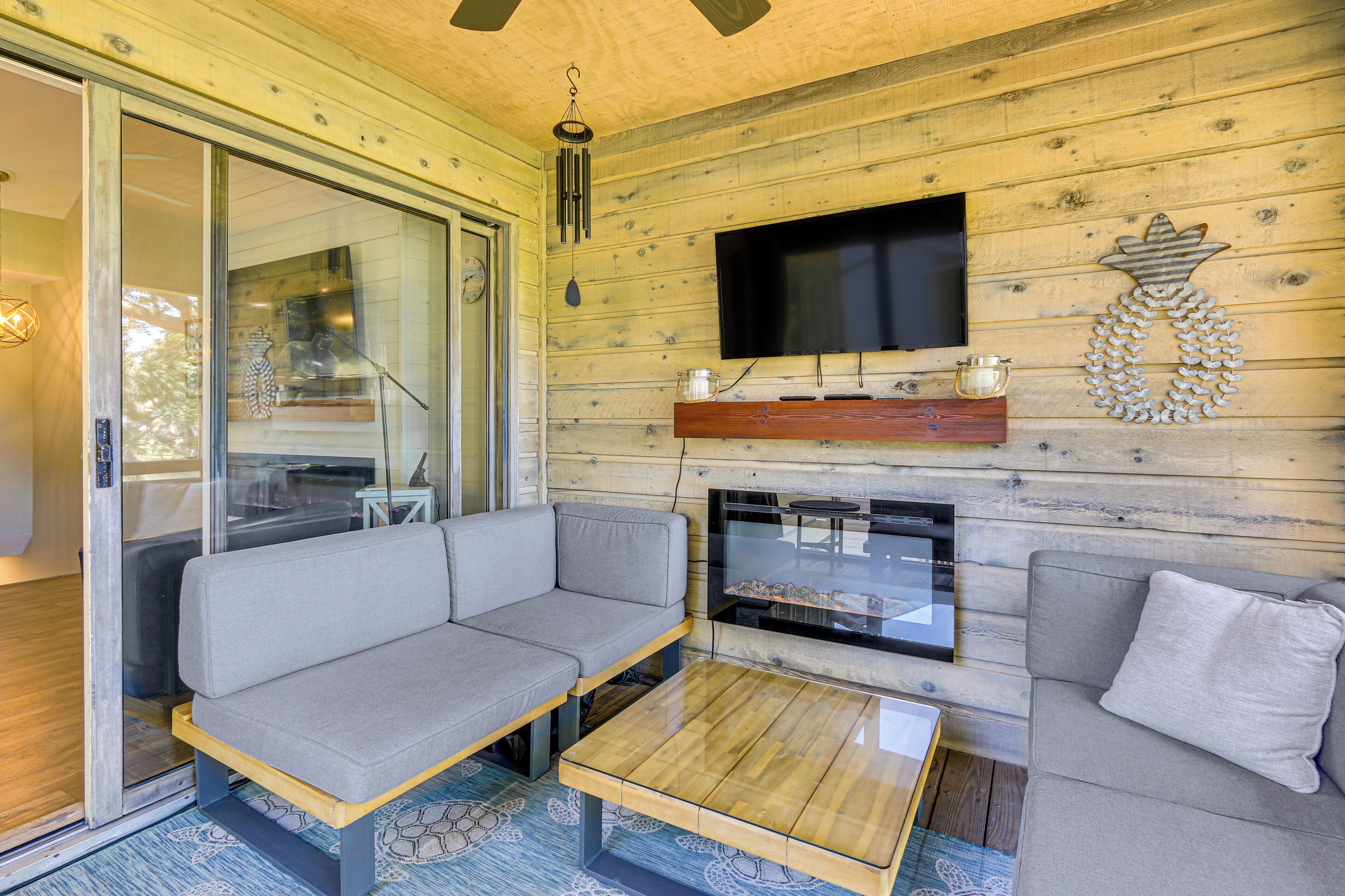 Una sala de estar acogedora con un sofá, una mesa de centro, una chimenea y un televisor montado en la pared.