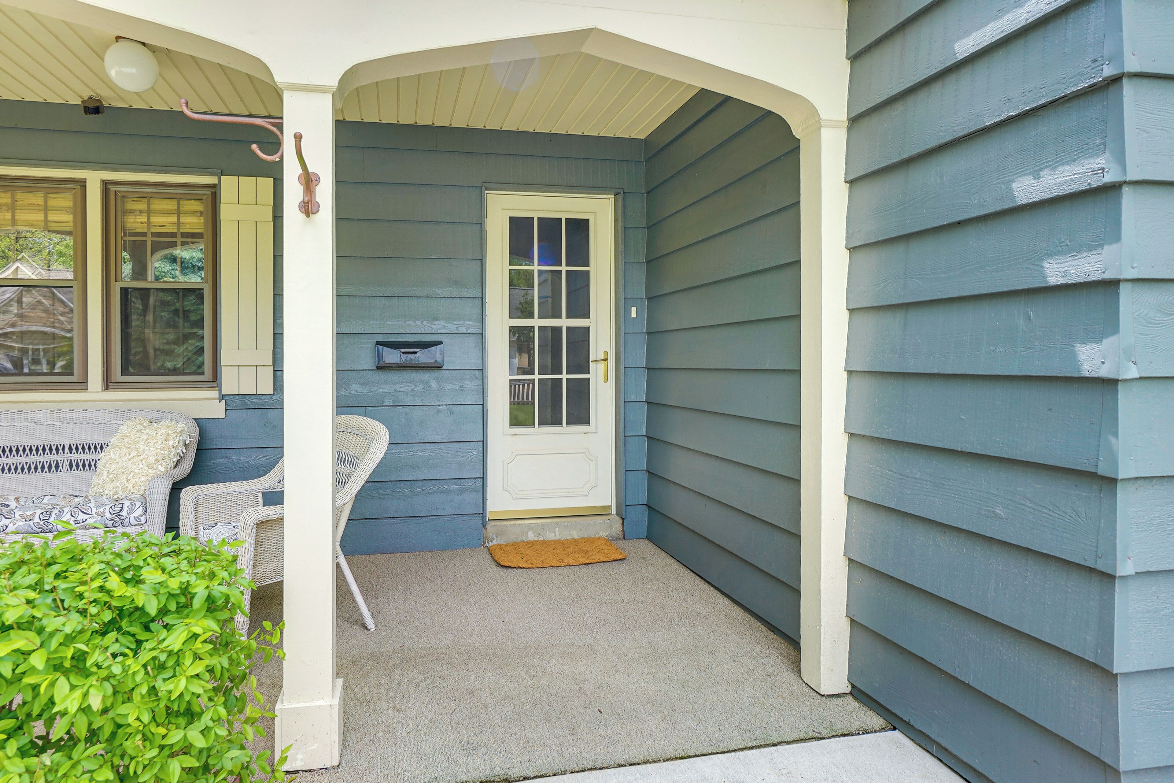 A porch with a white door, a mailbox, and a small rug.