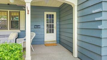 A porch with a white door, a mailbox, and a small rug.