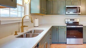 A kitchen with a stainless steel sink, a microwave, and an oven. - Walkable Thiensville Retreat Near Hiking! (Mequon)