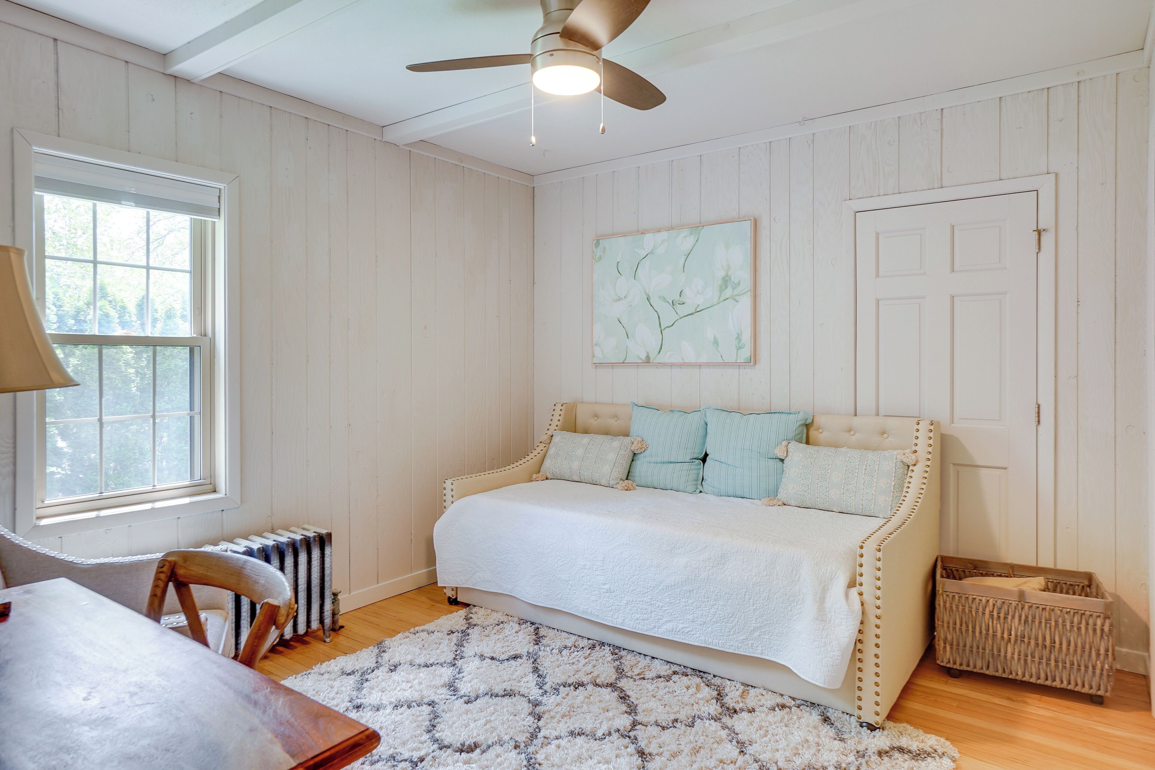 Une chambre à coucher avec un lit, un ventilateur de plafond, un radiateur, une fenêtre et une porte.