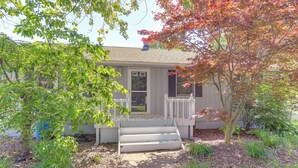 A house with a front porch, steps leading up to the door, and a small garden area with various plants. - Lake Erie Family Getaway in Amherst: Pets Welcome! (Amherst)