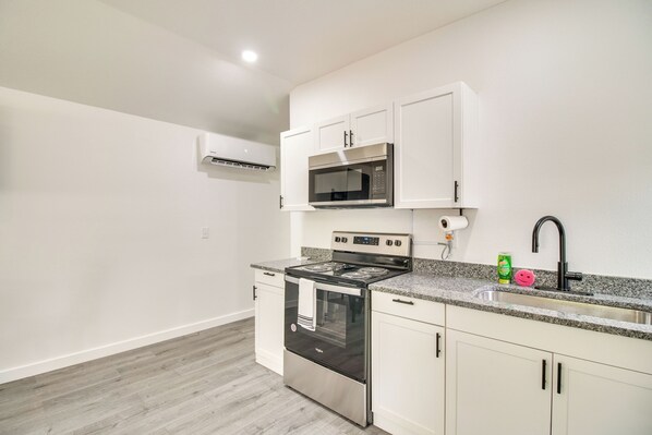 A kitchen with white cabinets, a stainless steel stove, a microwave, and a granite countertop.