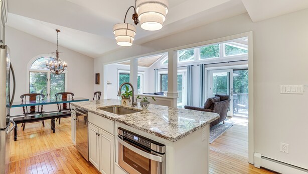 A modern kitchen with a large island, stainless steel appliances, and a glass-top dining table.