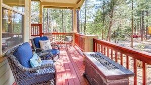 A covered porch with wicker furniture and a fire feature. - Walk to Rainbow Lake: Peaceful Cabin w/ Fire Pit (Lakeside)
