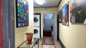 A hallway with a washing machine, a door marked "Employees Only," and a cityscape poster. - Quite Cozy Studio apartment (Philadelphia)