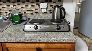 A kitchen with a gas stove, a kettle, and a bottle of dish soap on the counter. - Quite Cozy Studio apartment (Philadelphia)