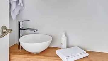 Une salle de bain avec un lavabo blanc, un robinet chromé et un plan de toilette en bois.