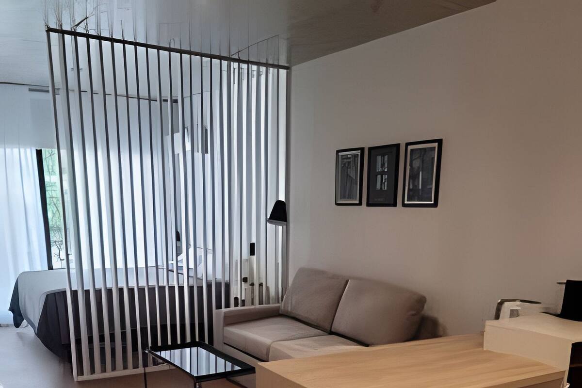 Een moderne woonkamer met een houten eettafel, witte stoelen, een bank en een glazen scheidingswand.