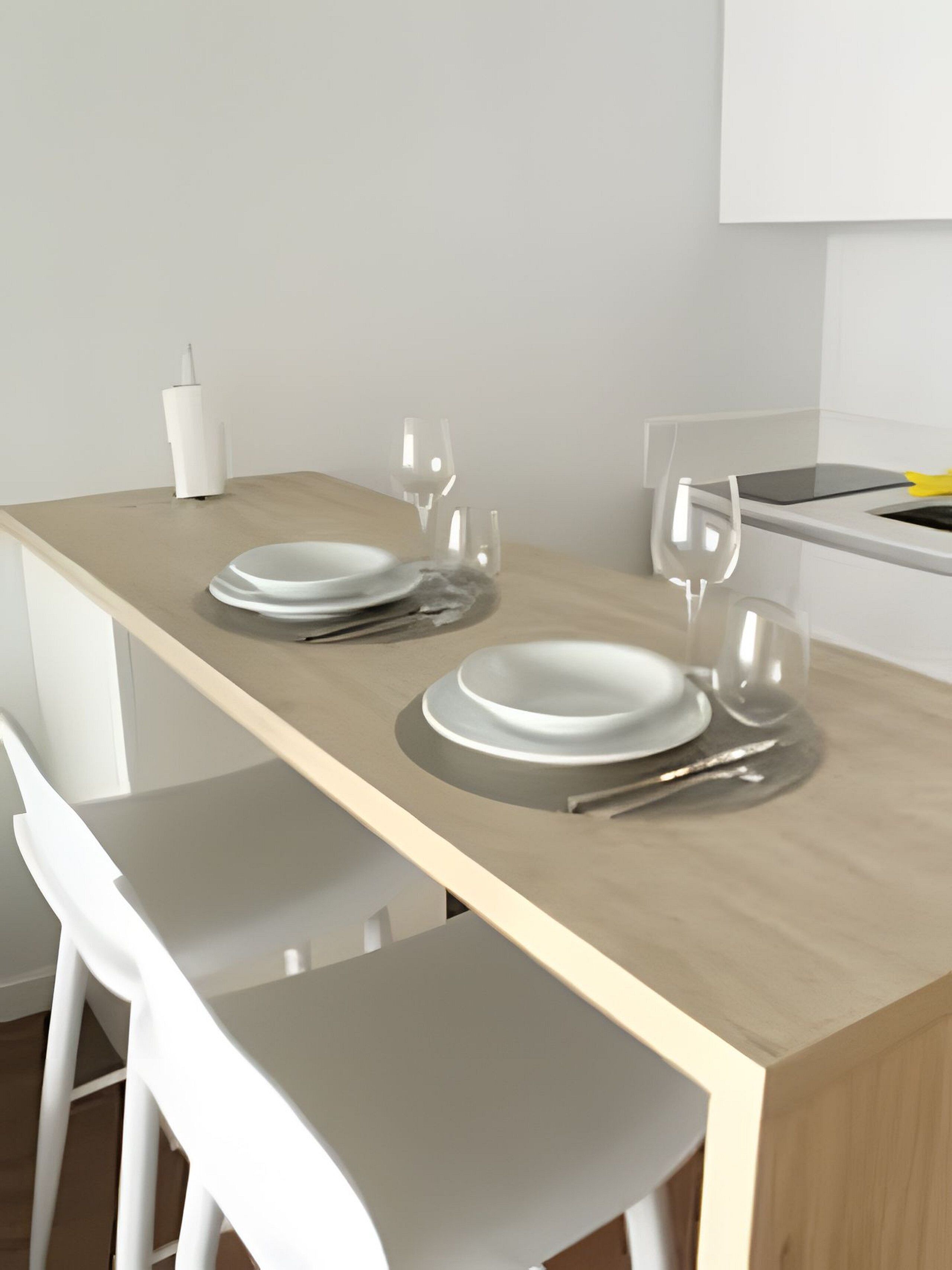 A modern kitchen with a wooden countertop, white chairs, and a white cabinet.